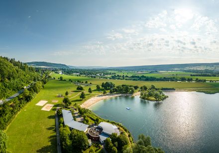 Luftbild von der Freizeitanlage Höxter-Godelheim. Zu sehen sind das Restaurant, sanitäre Anlagen, der Sandstrand sowie Spielgeräte.